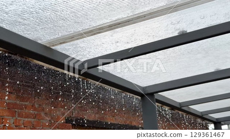 Heavy rain drumming on the transparent plexiglass roof. Beautiful rainy scene on summer day. Concept of tranquility nature scene. Close up Slow motion 129361467