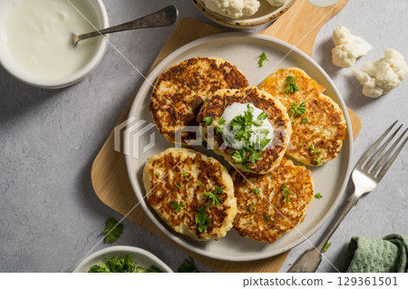 Vegetarian cauliflower pancakes, fritters served with sour cream  129361501