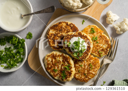 Vegetarian cauliflower pancakes, fritters served with sour cream Vegetarian cauliflower pancakes, fritters served with sour cream 129361510
