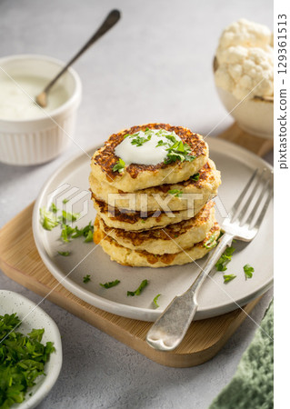 Vegetarian cauliflower pancakes, fritters served with sour cream  129361513