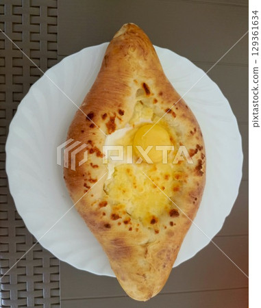 Traditional Georgian khachapuri in a rustic style in golden and yellow colors representing Caucasian cuisine and comfort food 129361634