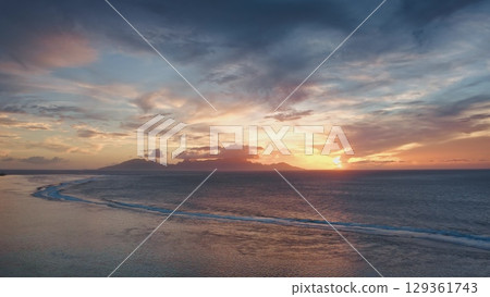 Breathtaking aerial view of Moorea island at sunset, with colorful clouds, calm ocean and gentle waves creating a mesmerizing tropical paradise in French Polynesia 129361743