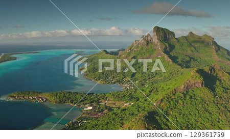 Aerial view of mountain Otemanu and surrounding coastline, showcasing the vibrant turquoise lagoon water and lush green tropical vegetation of Bora Bora island in French Polynesia. Travel background Aerial view of mountain Otemanu and surrounding coastline, showcasing the vibrant turquoise lagoon water and lush green tropical vegetation of Bora Bora island in French Polynesia. Travel background 129361759