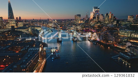 Illuminated Tower Bridge and The Shard glow in evening twilight, framing vibrant London skyline above the River Thames. Bright night lights, modern city architecture cityscape. Drone flight Illuminated Tower Bridge and The Shard glow in evening twilight, framing vibrant London skyline above the River Thames. Bright night lights, modern city architecture cityscape. Drone flight 129361832