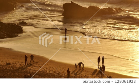 Lisbon, Portugal: Golden sunset casting a warm glow over the beach, with tourists walking along the shore, playing in the sand, and savoring the stunning scenery. Summer travel vacation background Lisbon, Portugal: Golden sunset casting a warm glow over the beach, with tourists walking along the shore, playing in the sand, and savoring the stunning scenery. Summer travel vacation background 129361928