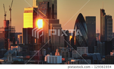 United Kingdom, London: London skyscrapers during a vibrant sunset. Warm sunlight reflecting in glass buildings, dynamic cityscape highlighting 30 St Mary Axe, the Gherkin. Aerial view drone United Kingdom, London: London skyscrapers during a vibrant sunset. Warm sunlight reflecting in glass buildings, dynamic cityscape highlighting 30 St Mary Axe, the Gherkin. Aerial view drone 129361934