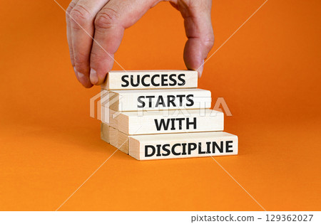 Success starts with discipline symbol. Concept words Success starts with discipline on beautiful wooden blocks. Beautiful orange background. Business success starts with discipline concept. Copy space Success starts with discipline symbol. Concept words Success starts with discipline on beautiful wooden blocks. Beautiful orange background. Business success starts with discipline concept. Copy space 129362027