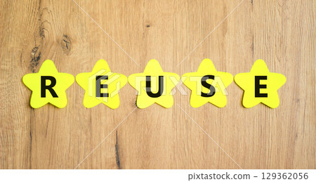 Reuse symbol. Concept word Reuse on beautiful yellow paper stars. Beautiful wooden table wooden background. Business lifestyle ecological reuse concept. Copy space. 129362056