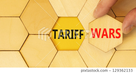 Trade tariff wars symbol. Concept word Tariff wars on beautiful wooden puzzles. Businessman's hand. Beautiful yellow paper background. Business trade tariff wars concept concept. Copy space. 129362133