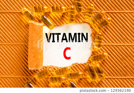 Vitamin C symbol. Concept words Vitamin C on beautiful white paper. Yellow pills tablets. Beautiful brown background. Medical healthy lifestyle Vitamin C concept. Vitamin C symbol. Concept words Vitamin C on beautiful white paper. Yellow pills tablets. Beautiful brown background. Medical healthy lifestyle Vitamin C concept. 129362190