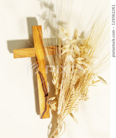 Wooden crucifixion with bouquet of wheat and rye on light background. Religion card suitable for faith religion, christian holidays, Easter, Redeemer, the Feast of Corpus Christi 129362261