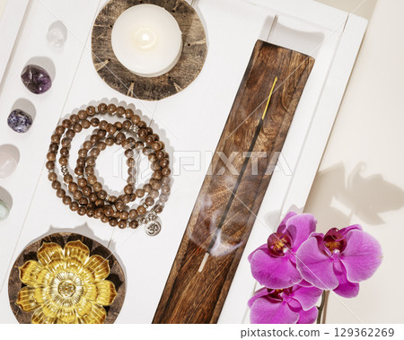 Self-care, healing flat lay with rosary beads, candles, aroma sticks, chakra stones and orchid flowers on a white wooden tray. Concept of me time, relaxing at home, energy healing and meditation Self-care, healing flat lay with rosary beads, candles, aroma sticks, chakra stones and orchid flowers on a white wooden tray. Concept of me time, relaxing at home, energy healing and meditation 129362269