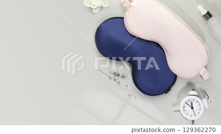 Sleep care composition with masks for sleep, alarm clock with time for sleep and lavender flowers on a grey background. Insomnia or depression treatment for sleepless nights. Mode for good sleep Sleep care composition with masks for sleep, alarm clock with time for sleep and lavender flowers on a grey background. Insomnia or depression treatment for sleepless nights. Mode for good sleep 129362270