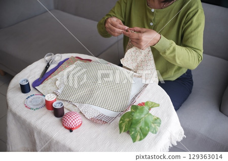 Senior women sewing clothes at home as hobby in her free time, sitting alone, leisure, relax, handcraft concept Senior women sewing clothes at home as hobby in her free time, sitting alone, leisure, relax, handcraft concept 129363014