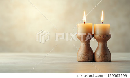Two beige candles in rustic wooden holders create warm ambiance 129363599