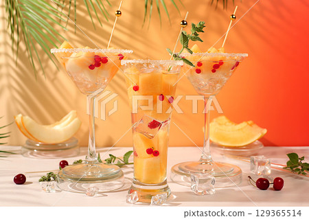 Melon alcoholic or non-alcoholic cocktail with mint. Martini, mojito and royal sangria with melon slices, ice, mint and currants. Summer party concept, advertising for a bar or cafe, detox diet Melon alcoholic or non-alcoholic cocktail with mint. Martini, mojito and royal sangria with melon slices, ice, mint and currants. Summer party concept, advertising for a bar or cafe, detox diet 129365514