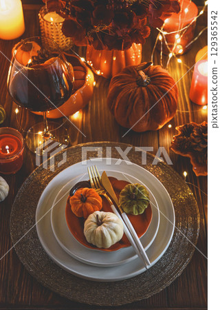 Autumnal table setting with decorative pumpkins, candles and string lights. Autumnal table setting with decorative pumpkins, candles and string lights. 129365542