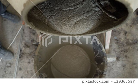 Construction worker pouring cement from mixer Construction worker pouring cement from mixer 129365587