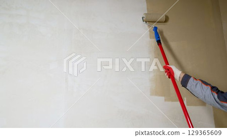 Painting walls with a roller. Painting a wall with a roller in yellow. 129365609