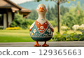 Charming goose figurine, adorned with intricately embroidered dress, stands on wooden surface 129365663