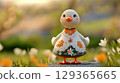 Goose figurine, dressed in floral pattern with delicate lace surrounded by flowers, copy space 129365665