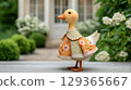 Goose figurine with embroidered dress, stands gracefully in garden on white flowers background 129365667