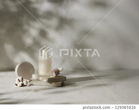 Open cosmetic serum bottle with dropper on stone slab with cotton flower in soft light and natural shadows 129365816