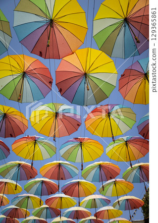 Many rainbow colored umbrellas against blue sky Many rainbow colored umbrellas against blue sky 129365861
