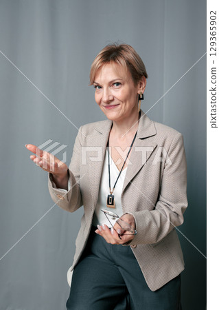 Happy woman. Confident, successful mature woman on light gray background. Looking at camera. High quality photo 129365902