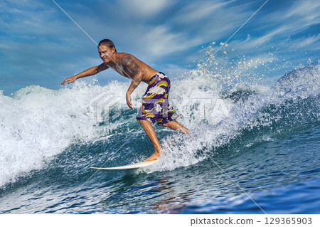 Male surfer on a blue wave 129365903