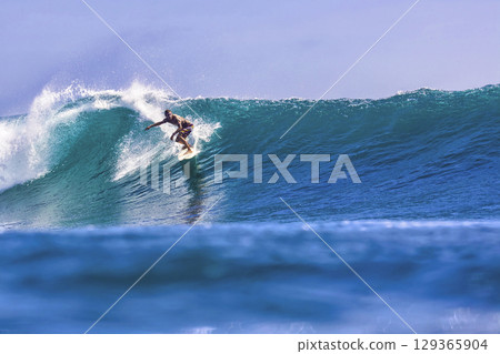 Male surfer on a blue wave 129365904