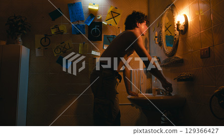 Man Washing His Face In Front Of The Bathroom Mirror 129366427