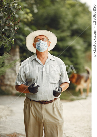 Old man in a medical mask. Man in the park. Coronavirus theme. 129366850