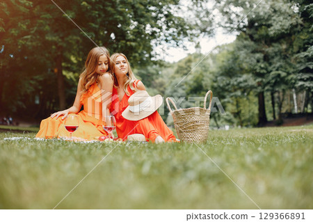 Beautiful girl in a red dress. Women sitting in a summer park. Beautiful girl in a red dress. Women sitting in a summer park. 129366891