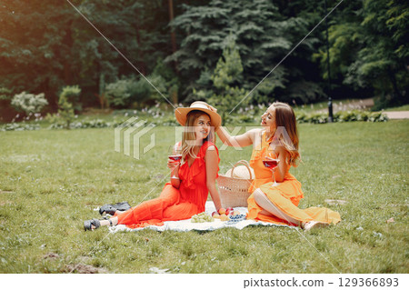Beautiful girl in a red dress. Women sitting in a summer park. 129366893