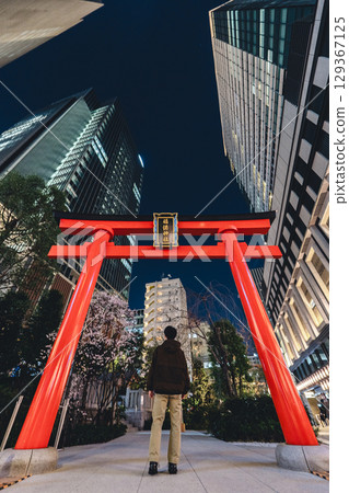 被摩天大樓包圍的福德神社紅色鳥居（夜景）和一個人的背影 129367125