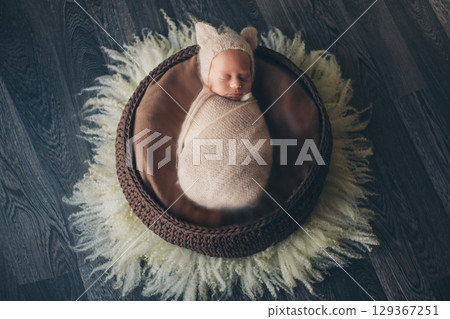 A newborn baby is wrapped in diapers with a wool cap in a basket. Swaddling, maternity hospital, family, ivf, life planning, parenting. A mother's love for her child. Baby food. High quality photo 129367251
