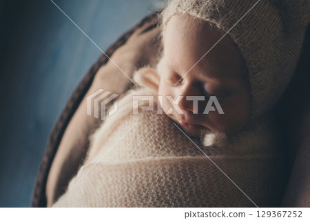 A newborn baby is wrapped in diapers with a wool cap in a basket. Swaddling, maternity hospital, family, ivf, life planning, parenting. A mother's love for her child. Baby food. High quality photo A newborn baby is wrapped in diapers with a wool cap in a basket. Swaddling, maternity hospital, family, ivf, life planning, parenting. A mother's love for her child. Baby food. High quality photo 129367252