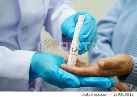 Asian doctor using digital glucose meter for check sample blood sugar level to treatment diabetes. Asian doctor using digital glucose meter for check sample blood sugar level to treatment diabetes. 129368012