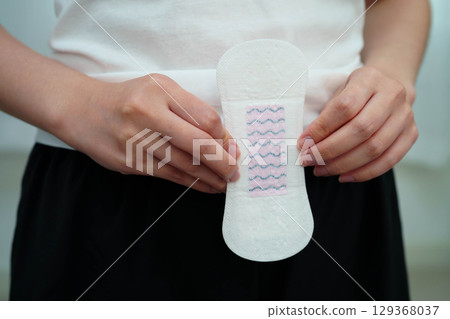 Asian woman holding sanitary napkin pad for hygiene menstrual period cycle protection. 129368037