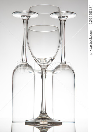 Crystal-clear wine glasses with delicate stems line up, their reflections enhancing 129368184