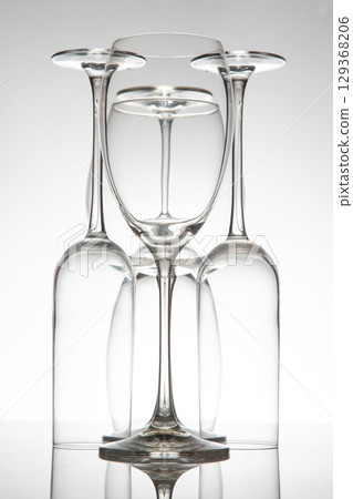 Crystal-clear wine glasses with delicate stems line up, their reflections enhancing the composition 129368206