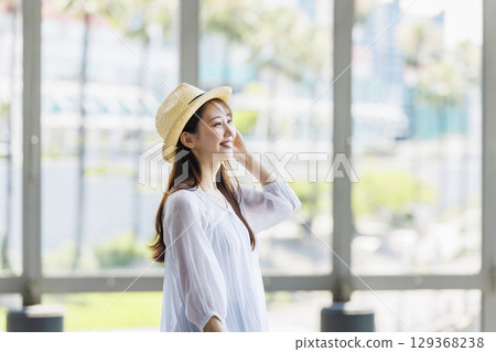 A young woman wearing a straw hat enjoying sightseeing 129368238