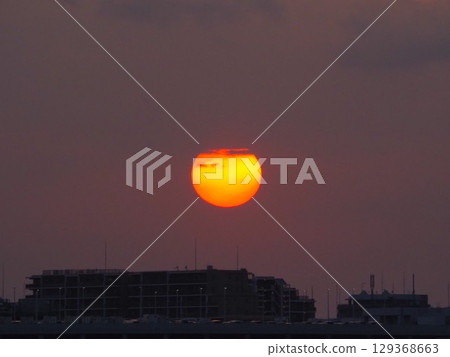 The setting sun peeking out from between the clouds The setting sun peeking out from between the clouds 129368663