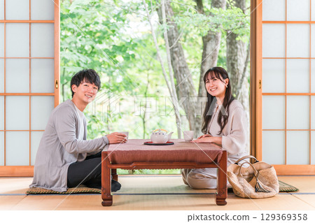 Couple drinking tea in a Japanese-style room at a ryokan with a garden view 129369358