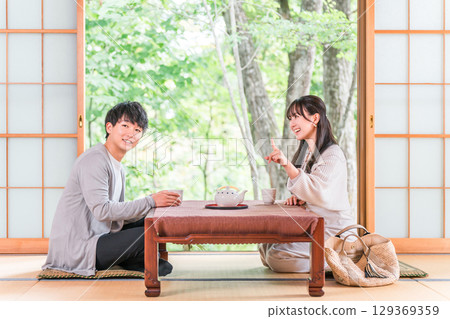 Couple drinking tea in a Japanese-style room at a ryokan with a garden view 129369359
