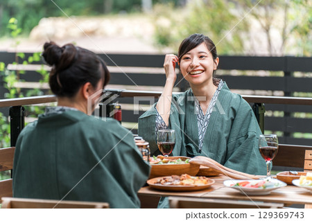 Young Asian woman on a girls trip to a Japanese inn/hot spring inn eating on a balcony/wooden deck (travel/travel) 129369743