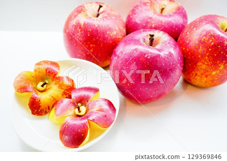 Cute apples cut into the shape of a flower on a white background indoors 129369846