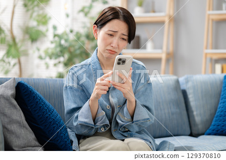 A woman using a smartphone in the living room 129370810