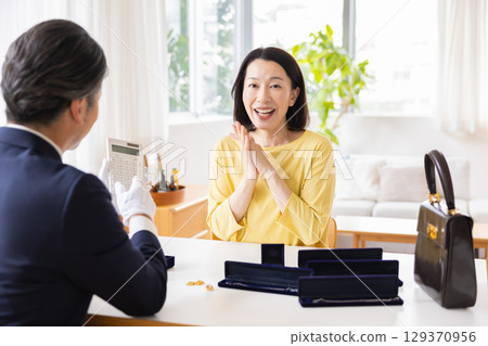 現場購買:一位家庭主婦正在家中評估她的物品 現場購買:一位家庭主婦正在家中評估她的物品 129370956